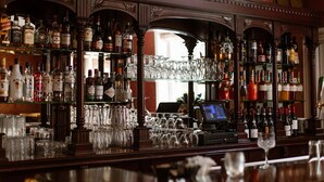 Zona de bar con estanterías llenas de botellas de licor y una caja registradora.