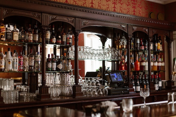 Un espace bar avec des étagères remplies de bouteilles d’alcool et une caisse enregistreuse.