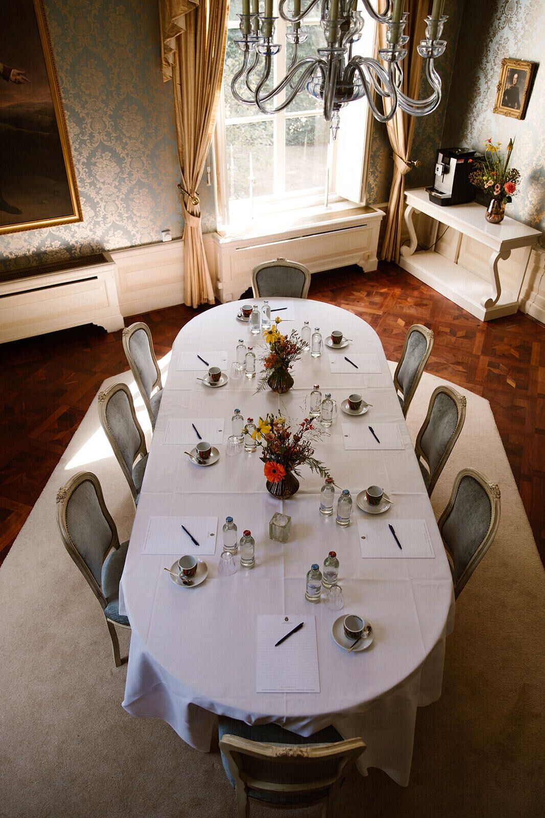 Un comedor formal con una mesa redonda dispuesta para una comida, rodeada de sillas.