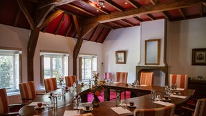 Una sala de conferencias con una gran mesa ovalada, sillas a rayas y una chimenea.