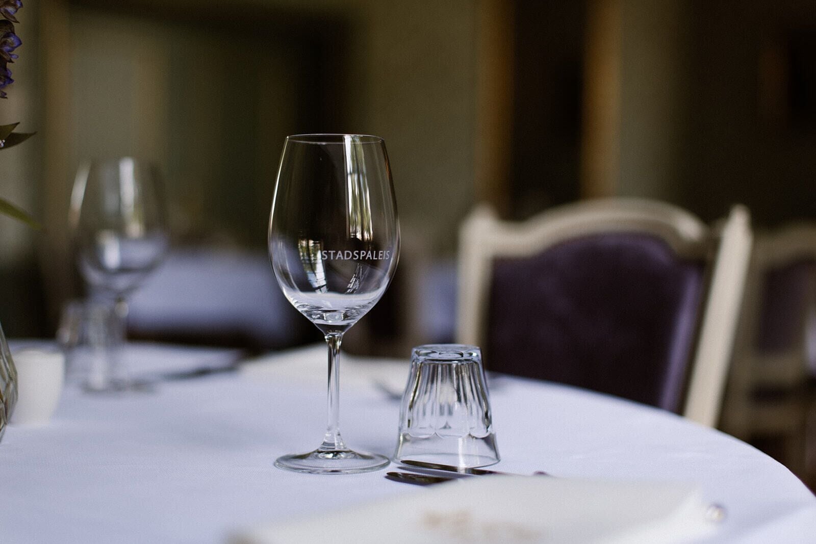 Una mesa de comedor con una copa de vino y un salero, sobre un mantel blanco.