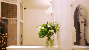 A bathroom with a vase of flowers on the counter, a mirror, and a chandelier. - Hotel Makedonia (London)