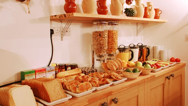 A buffet with bread, pastries, fruits, and condiments. - Hotel Makedonia (London)