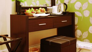 A wooden desk with a mirror, a basket of fruit, a coffee maker, and a small stool. - Hotel Makedonia (London)