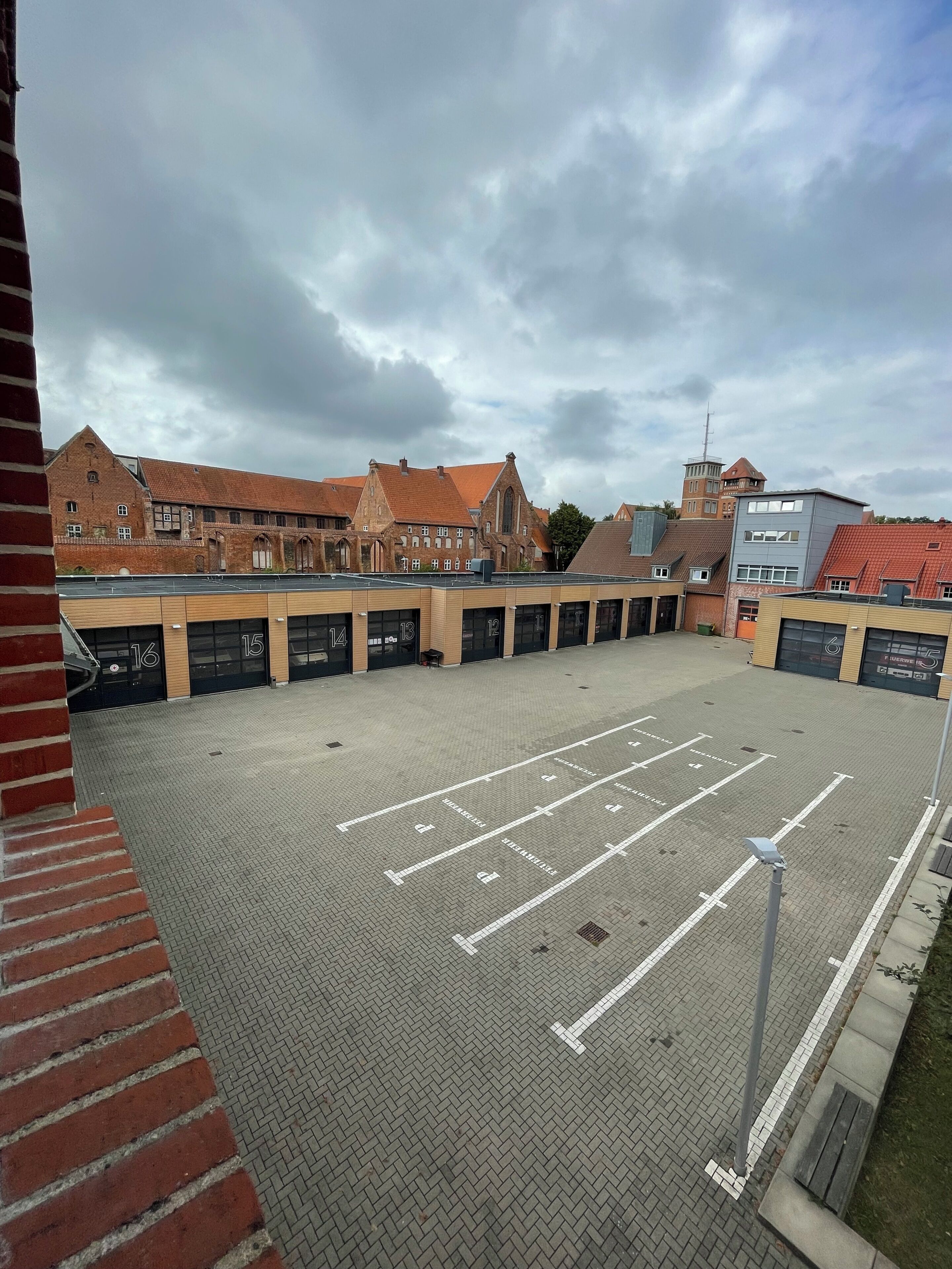 Un parking avec des places délimitées, situé à côté d’un bâtiment dont les portes de garage sont numérotées.