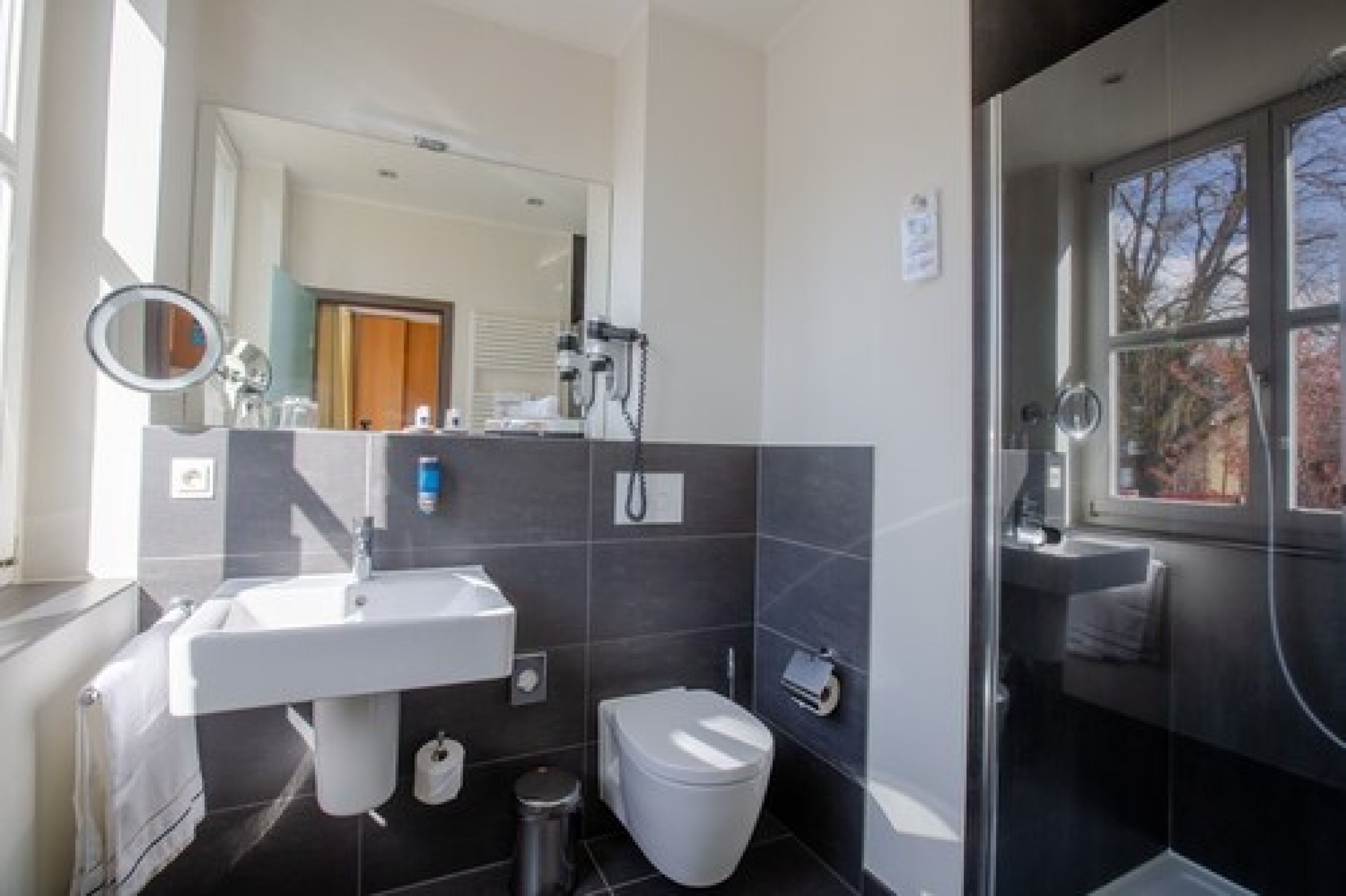 Een moderne badkamer met een witte wastafel, toilet en douchehoek.