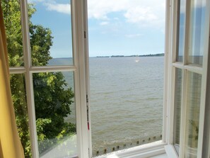 A view through a window of a body of water, with a distant shoreline and trees. - Hotel Hafenresidenz Stralsund (Stralsund)