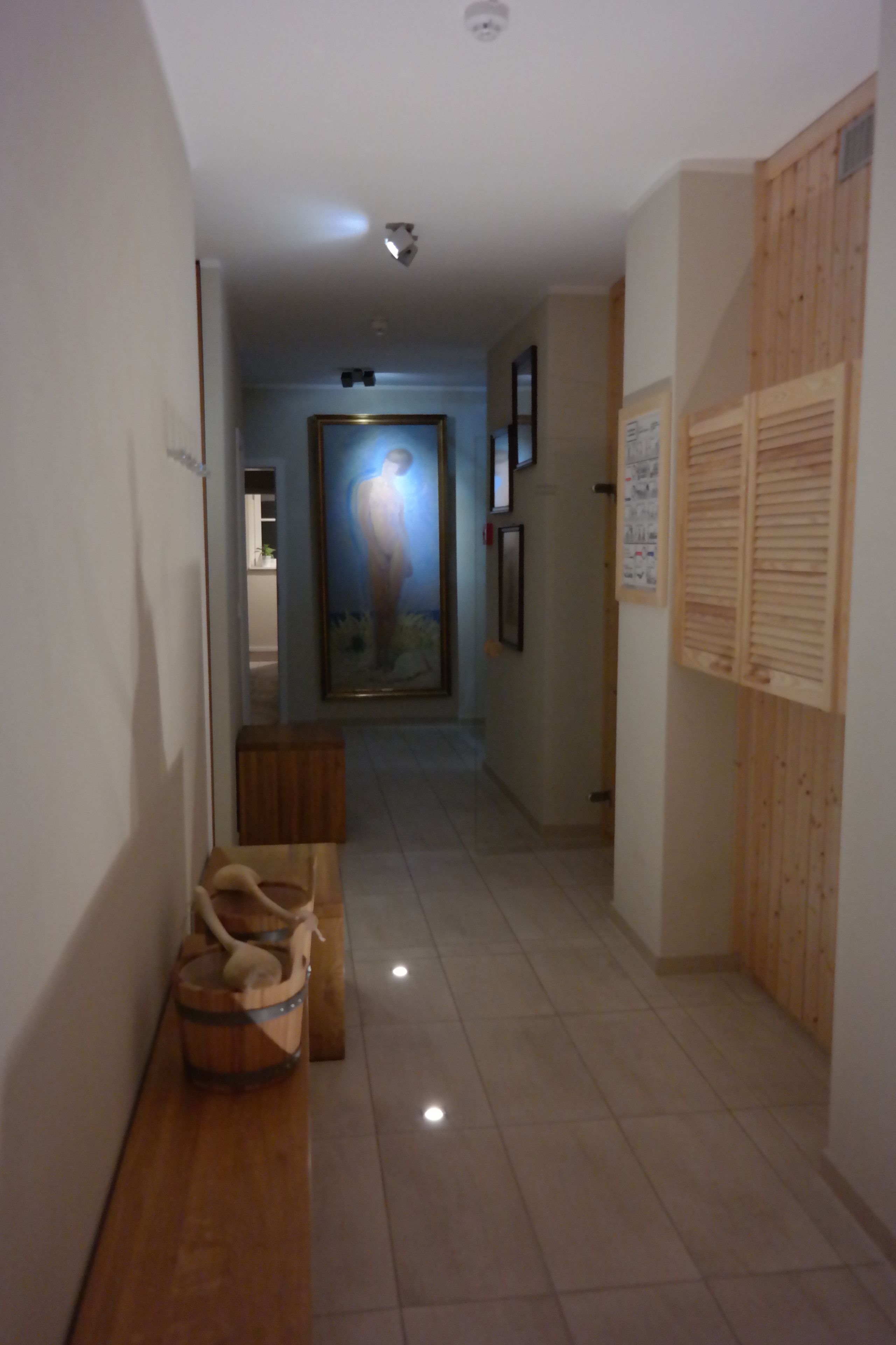 Un pasillo con un banco de madera, un cuadro en la pared y una puerta al final.