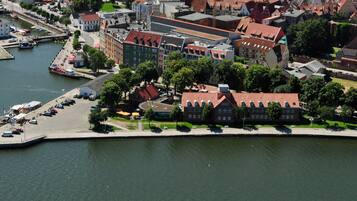 Luchtbeeld van een rivierstad met historische gebouwen, een jachthaven en een voetpad langs de rivier.