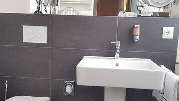 Une salle de bain moderne équipée de toilettes, d’un lavabo et d’un miroir.