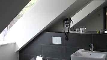 A modern bathroom with a skylight, a toilet, a sink, and a trash bin.