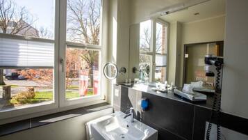 A modern bathroom with a large window, a sink, a mirror, and a telephone.