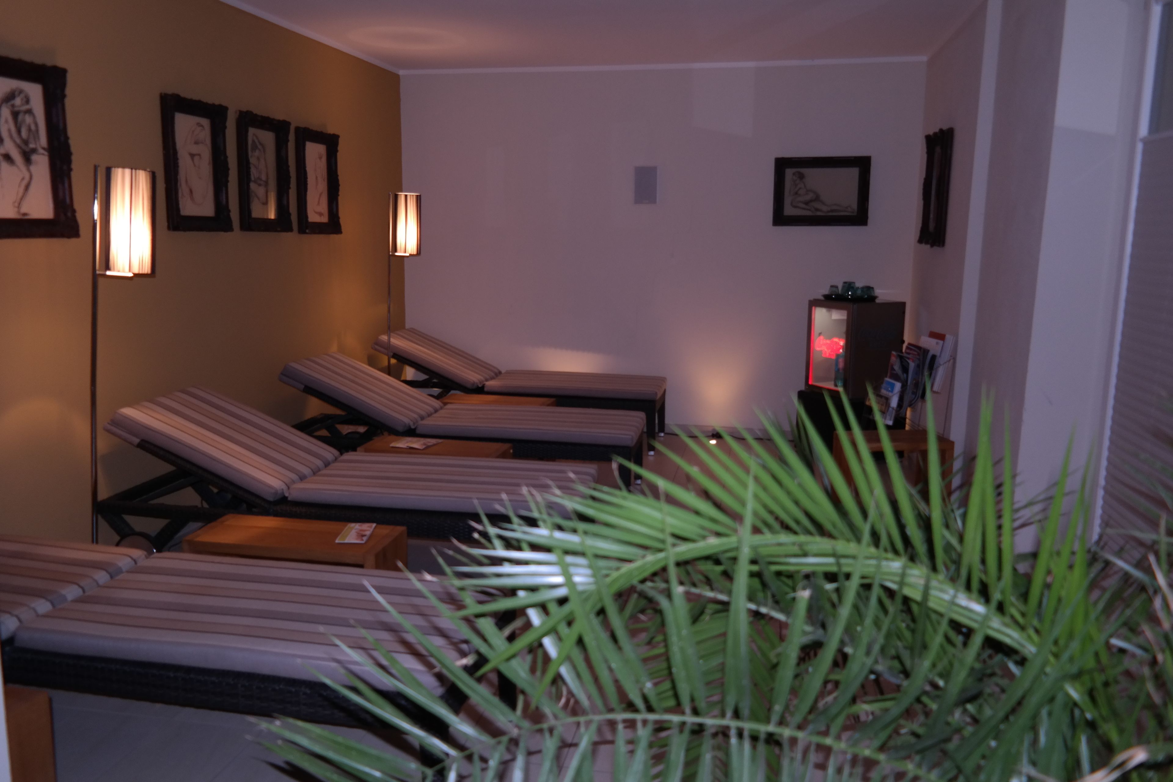 A room with four reclining chairs, a small table, and a potted plant.