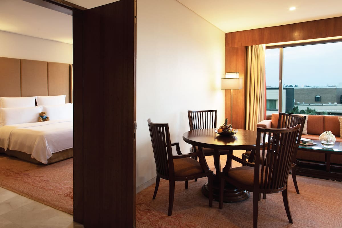 A hotel room with a bed, a dining table with chairs, and a sofa.