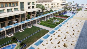 Un hôtel comprenant plusieurs étages, doté de piscines extérieures et d’un jardin bien entretenu.