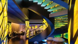 Un interior moderno con una escalera curva, iluminación ambiental y detalles decorativos.