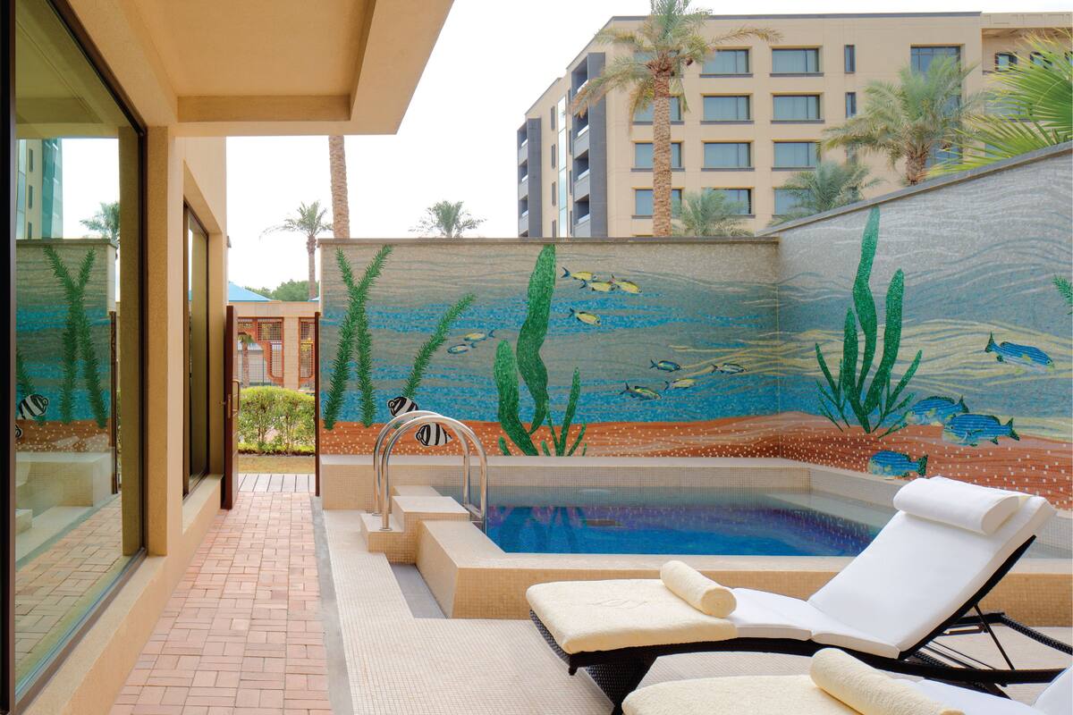 Zona de piscina con un mural, una silla de descanso y una escalera para la piscina.