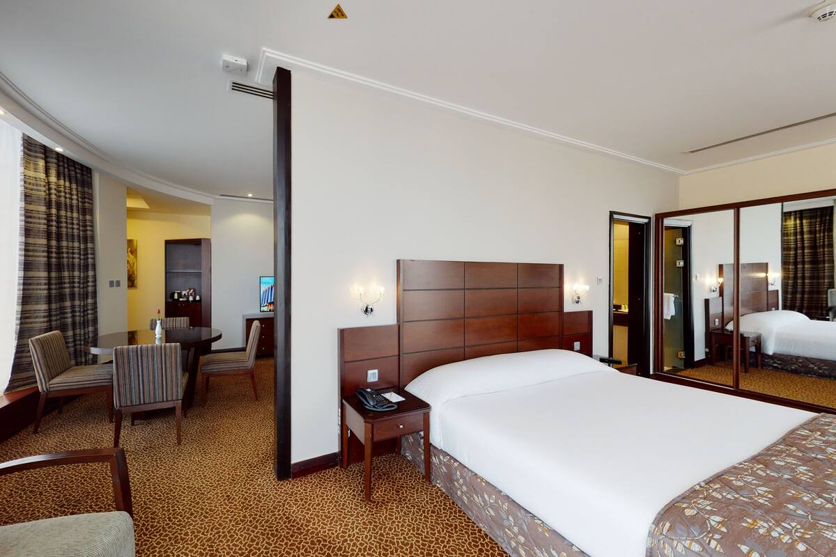 Una habitación de hotel con una cama grande, un escritorio con silla, un sofá y un espejo.