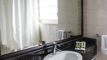 A modern bathroom with a large mirror, a white sink, and a black countertop.