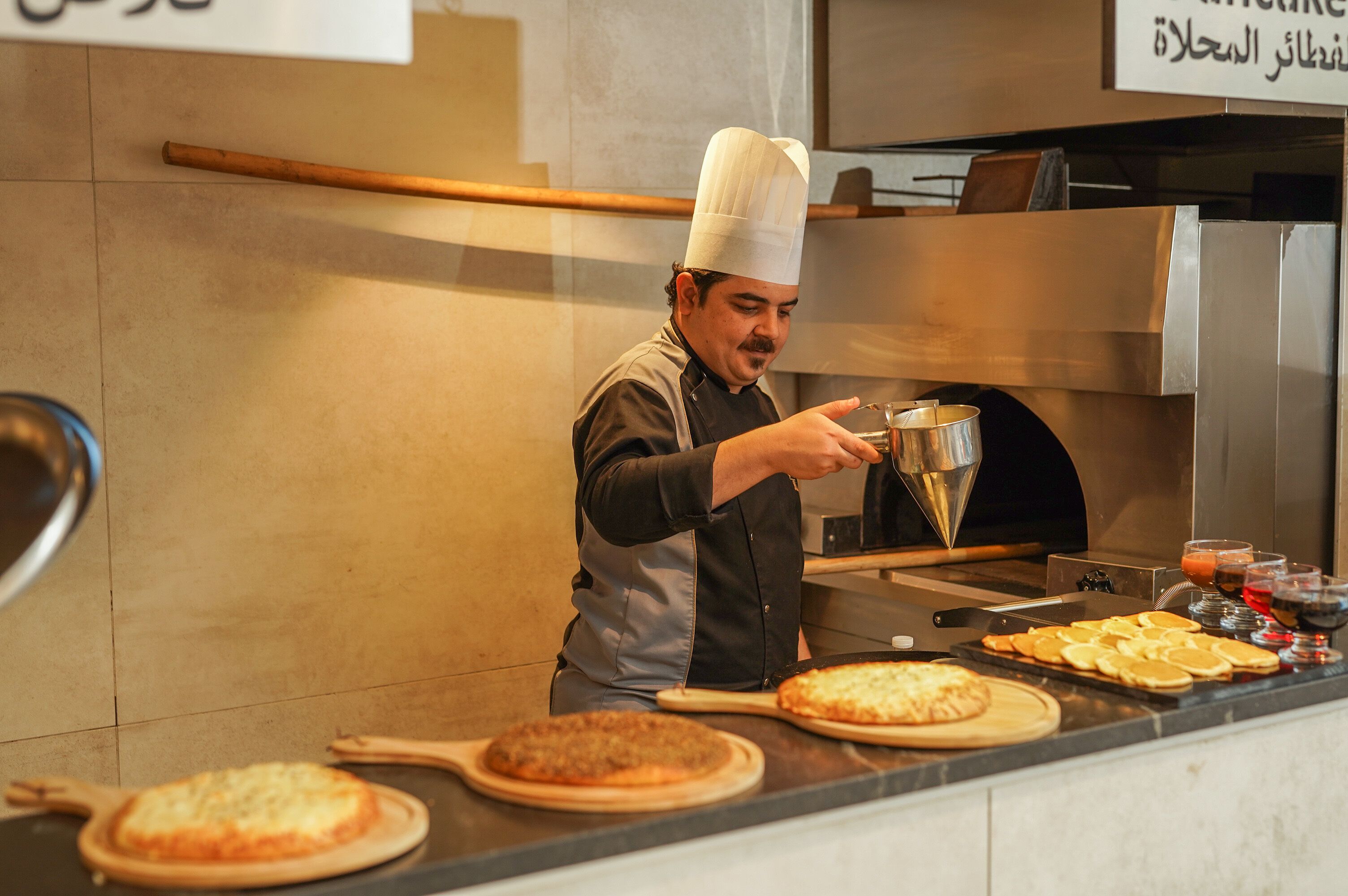 A chef preparing food in a kitchen with a pizza oven and various cooking utensils.