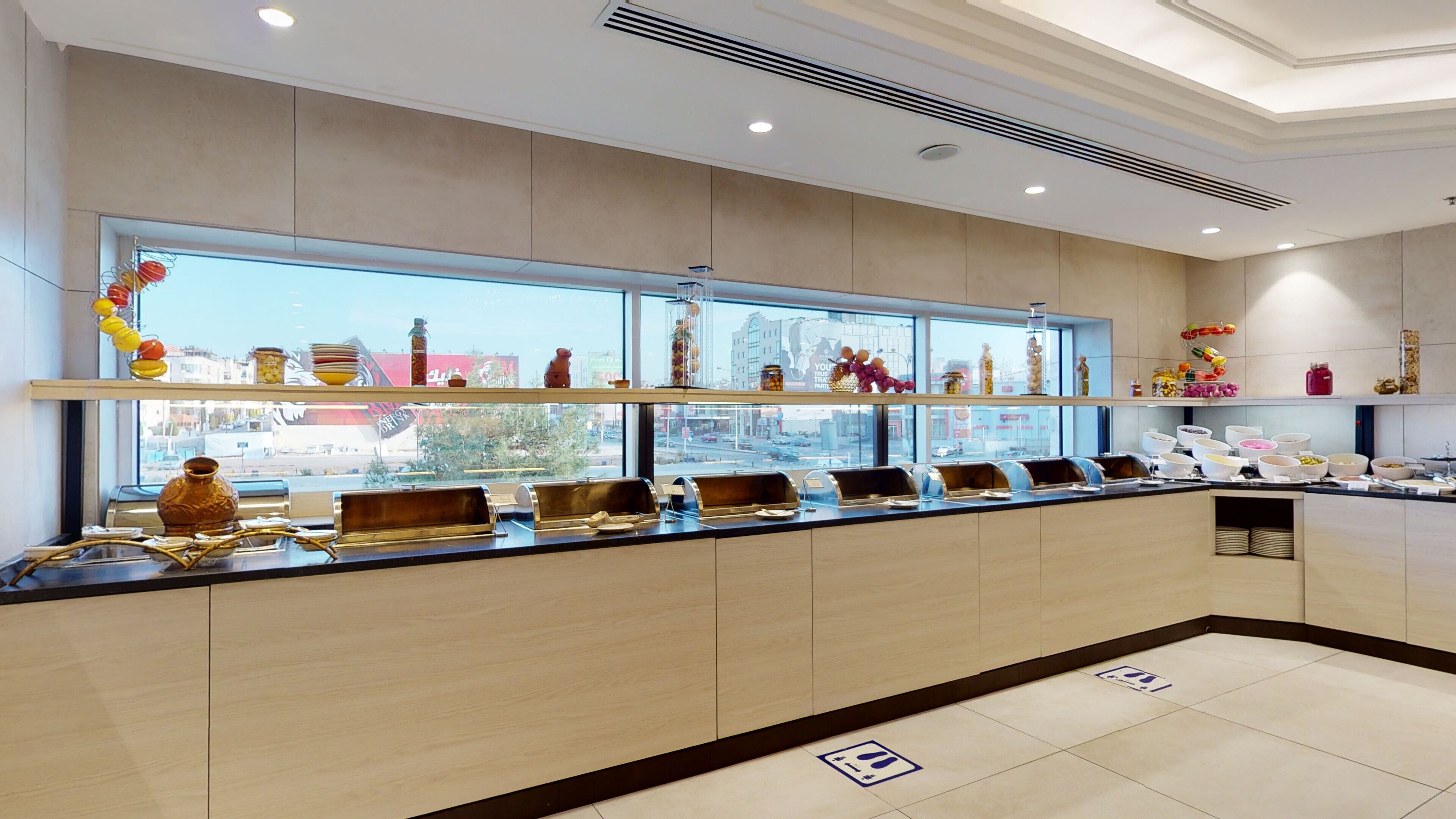 A modern breakfast bar with a view of the city, equipped with various food dispensers and decorative items.