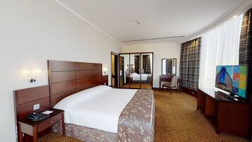 Una habitación de hotel con una cama grande, un escritorio, una silla, un televisor y un espejo.