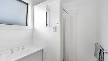 A modern bathroom with a white sink, mirror, and towel rack.