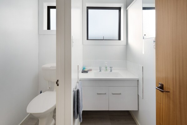 Un baño pequeño y moderno con inodoro, lavamanos y mueble de almacenamiento.