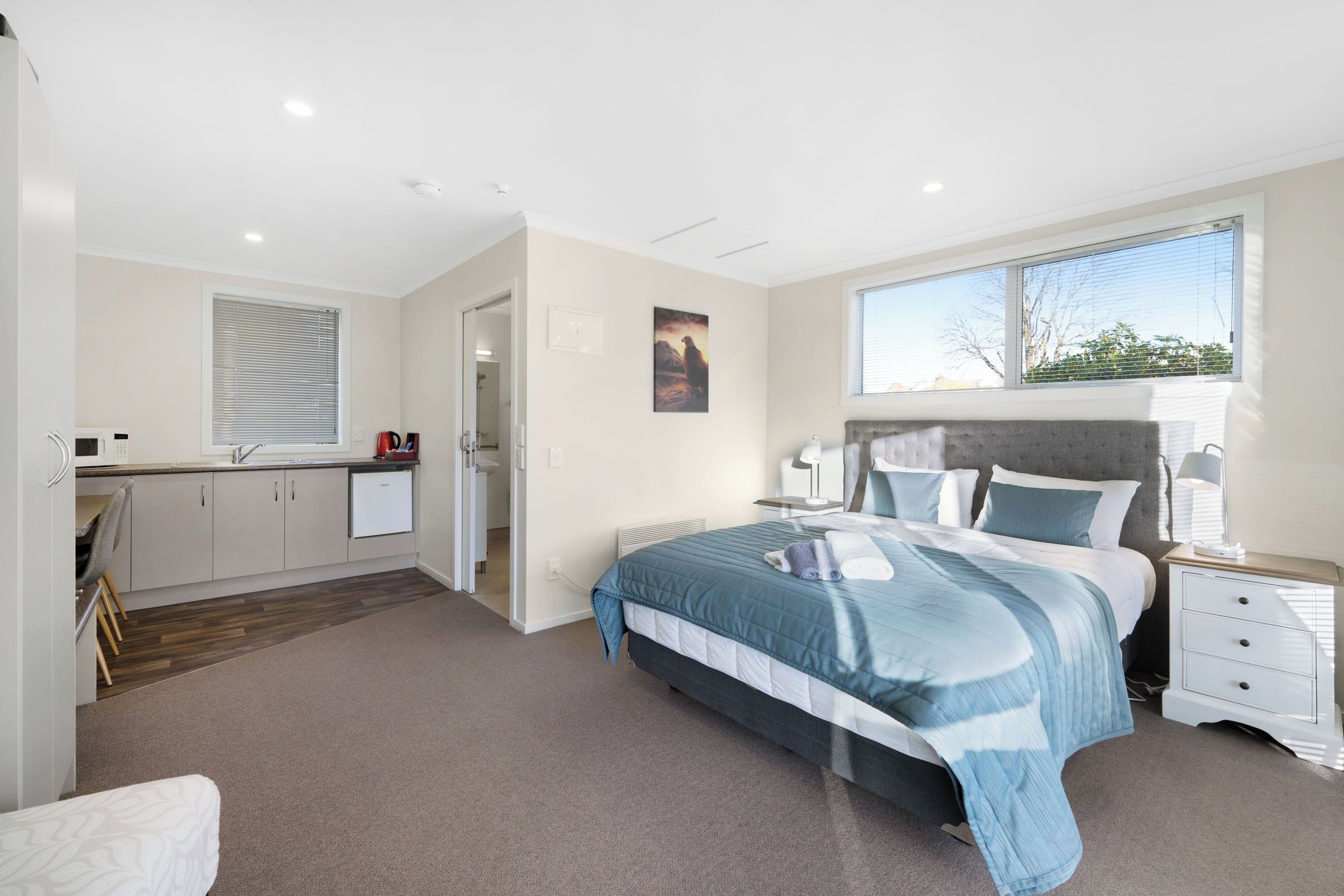 A bedroom with a bed, bedside table, and a window.