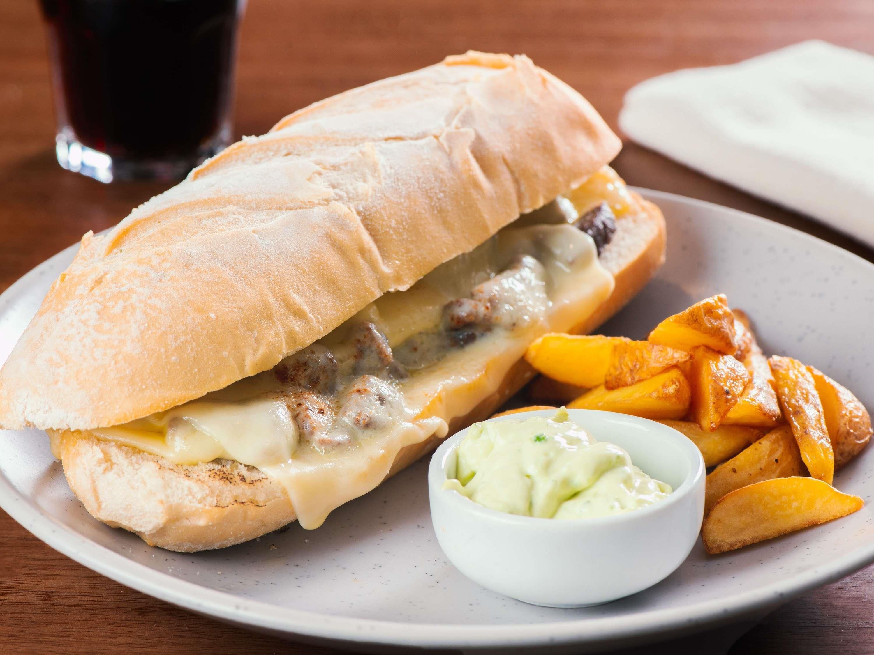 A sandwich with fries and a dipping sauce on a plate.
