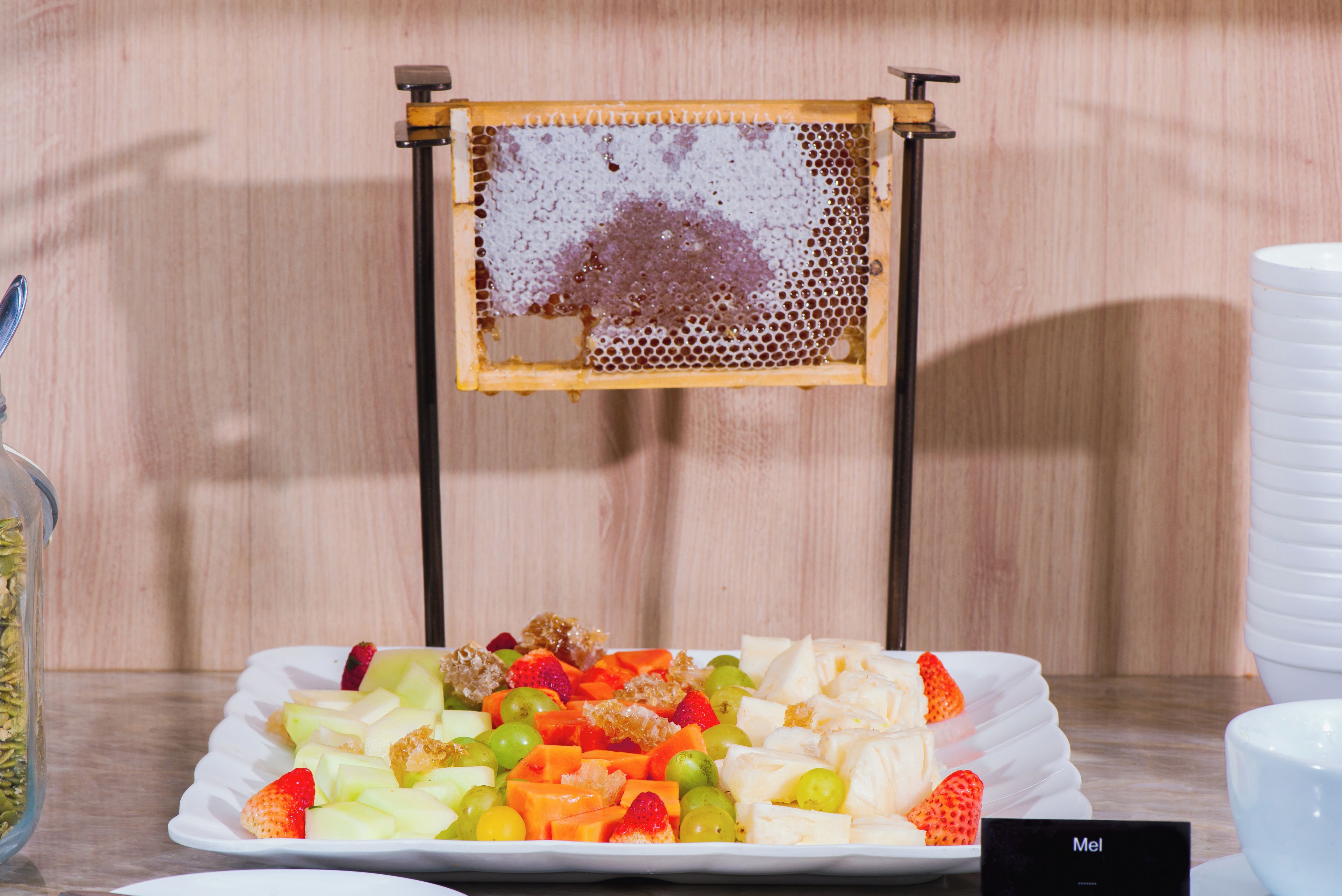 Una bandeja con frutas variadas y un panal sobre un soporte.