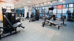 A modern gym with various exercise equipment, large windows, and a flat-screen TV. - Ibis Curitiba Shopping (Curitiba)