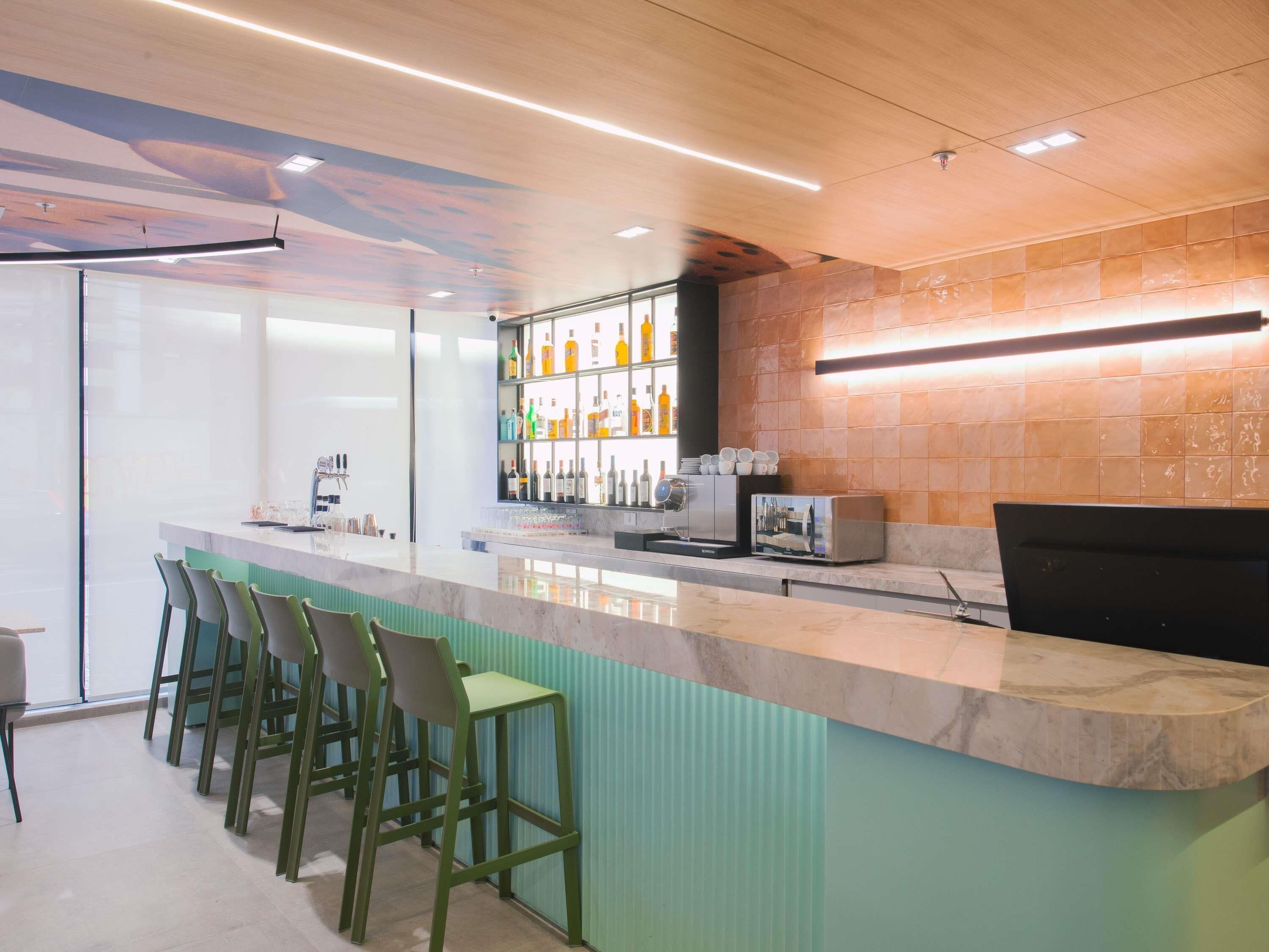A bar area with a counter, stools, and a wall of bottles.