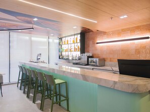 A bar area with a counter, stools, and a wall of bottles. - Ibis Curitiba Shopping (Curitiba)