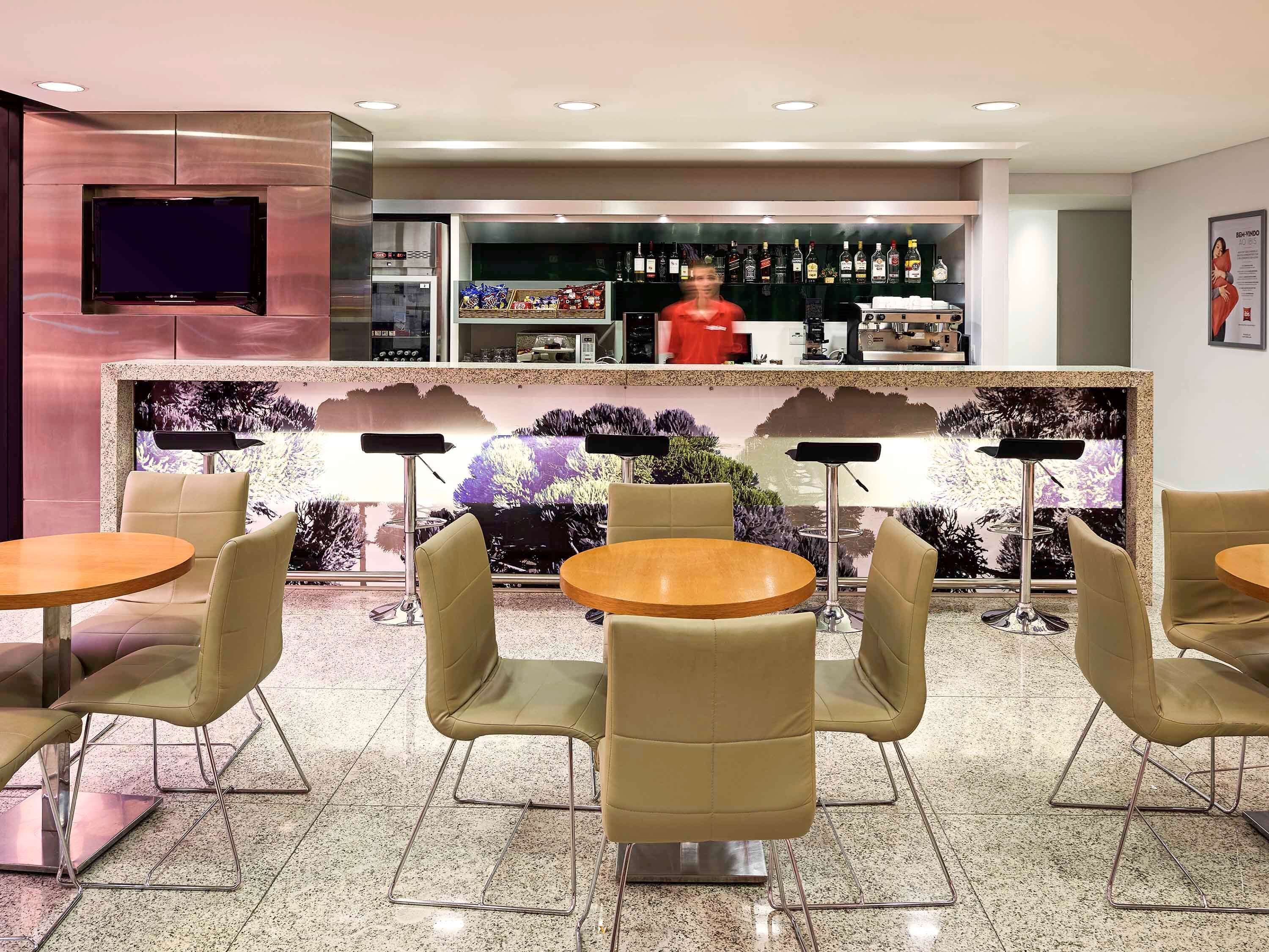 A modern bar area with a counter, bar stools, and a television screen.