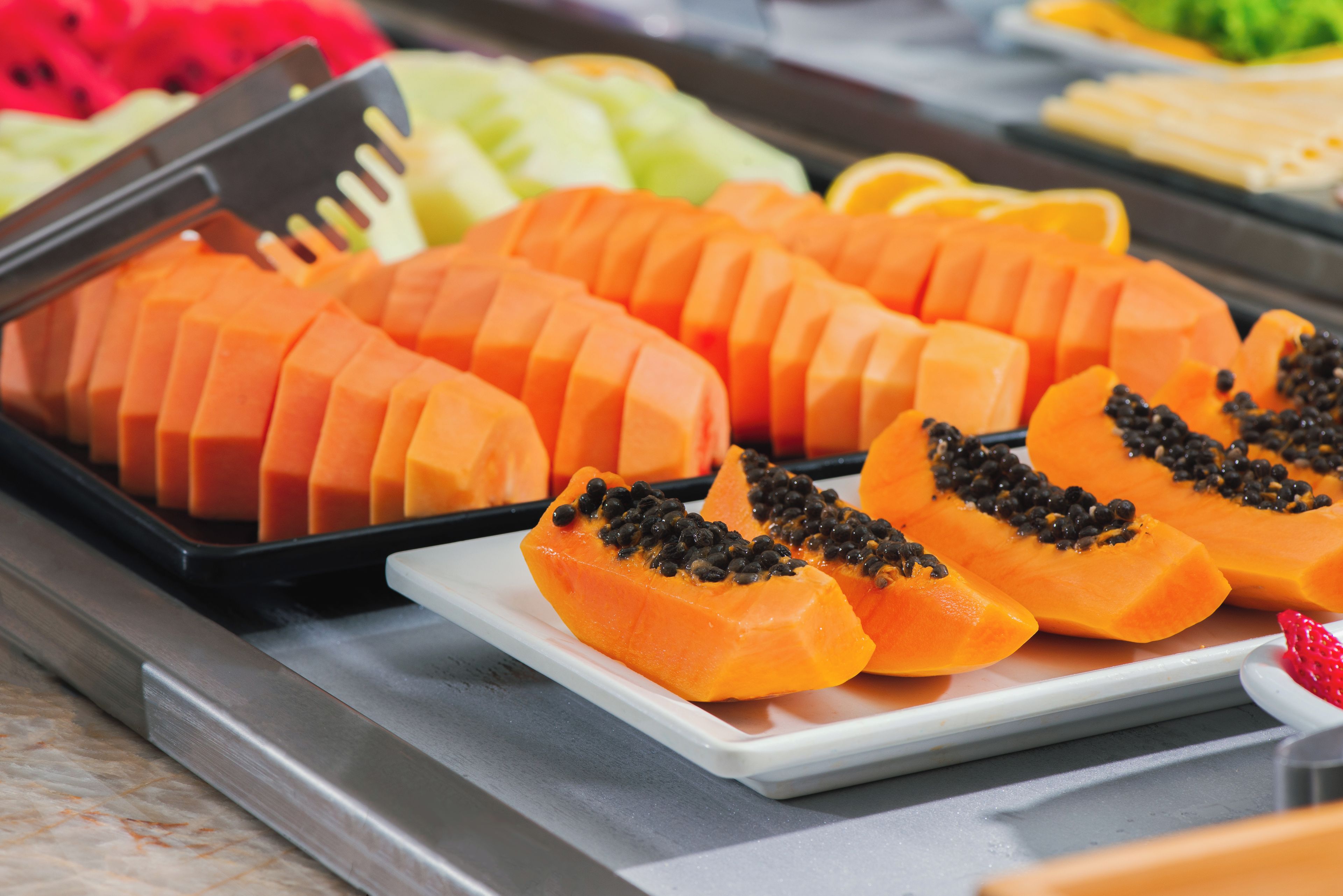 A tray of sliced papayas with black seeds on a white plate.