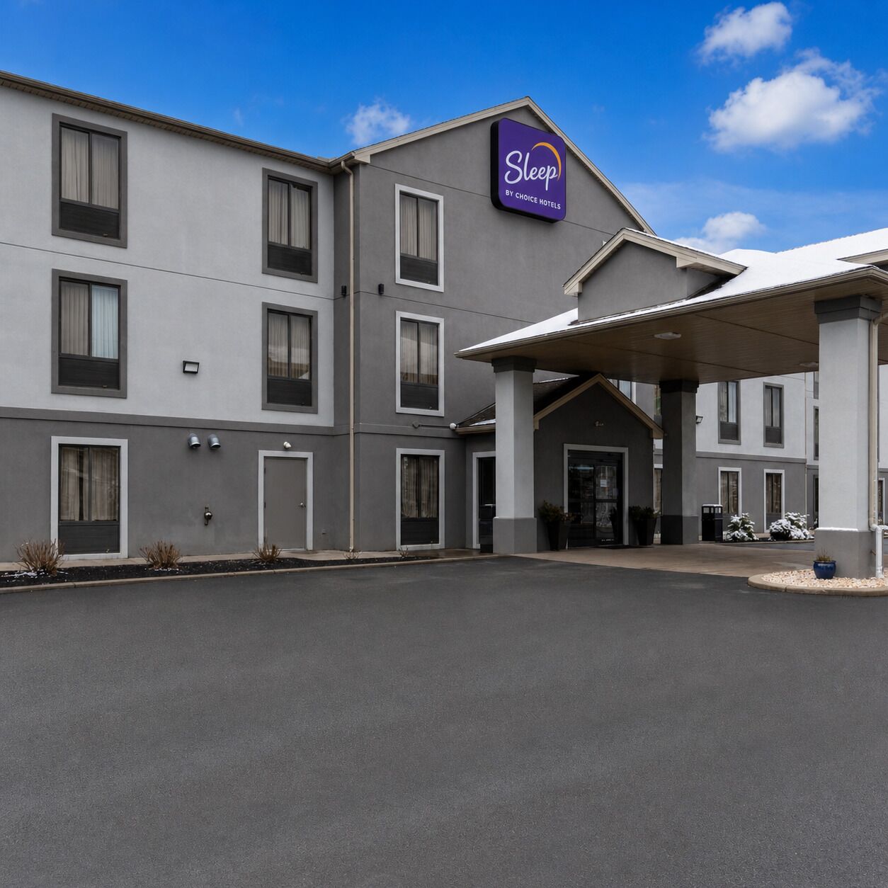 A Sleep by Choice Hotel building with a covered entrance, multiple windows, and a parking lot.