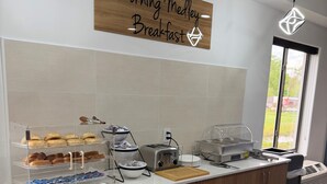 A breakfast bar with bread, pastries, and a toaster.