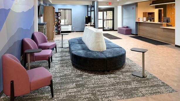A lobby with a reception desk, seating area, and a large window.