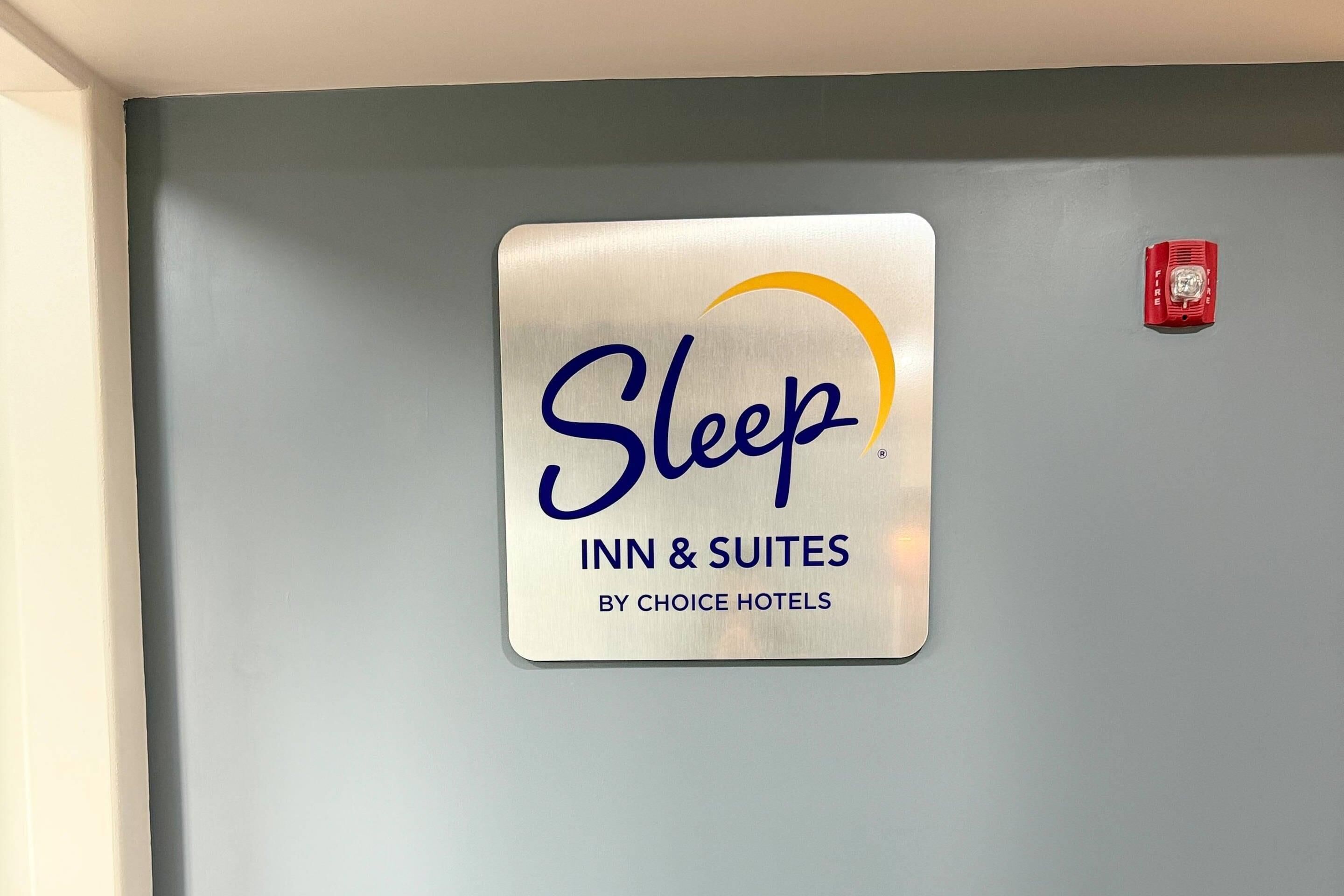 A sign for Sleep Inn & Suites by Choice Hotels on a grey wall.