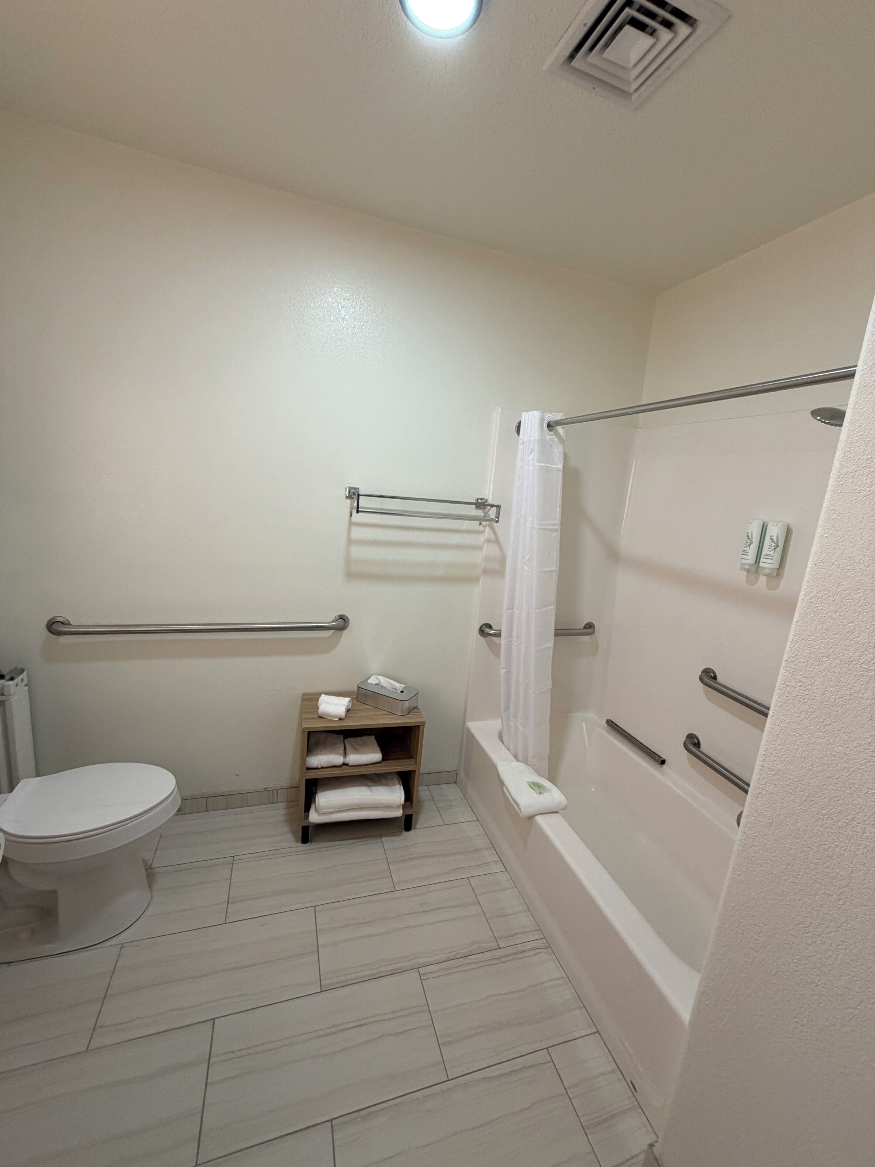 A bathroom with a toilet, a sink with a mirror, a shower with a glass door, and a towel rack.