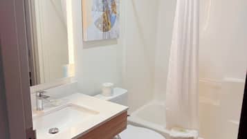 Un baño con lavamanos, inodoro y ducha blancos.