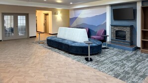 Una sala de estar moderna con un sofá azul, chimenea, televisor montado y suelo con patrón de espiga.