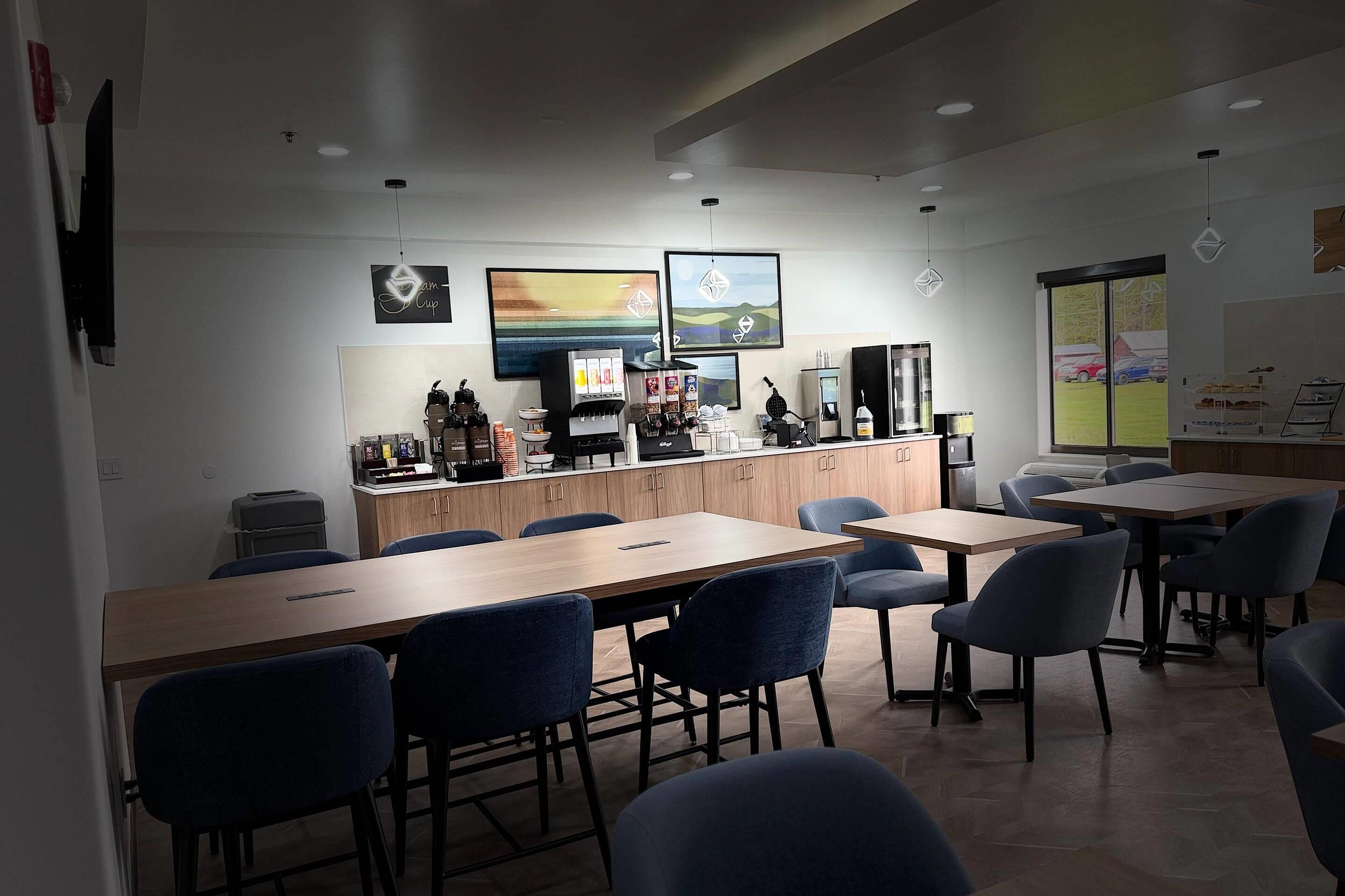Una cafetería moderna con mostrador, zona de mesas y obras de arte en las paredes.