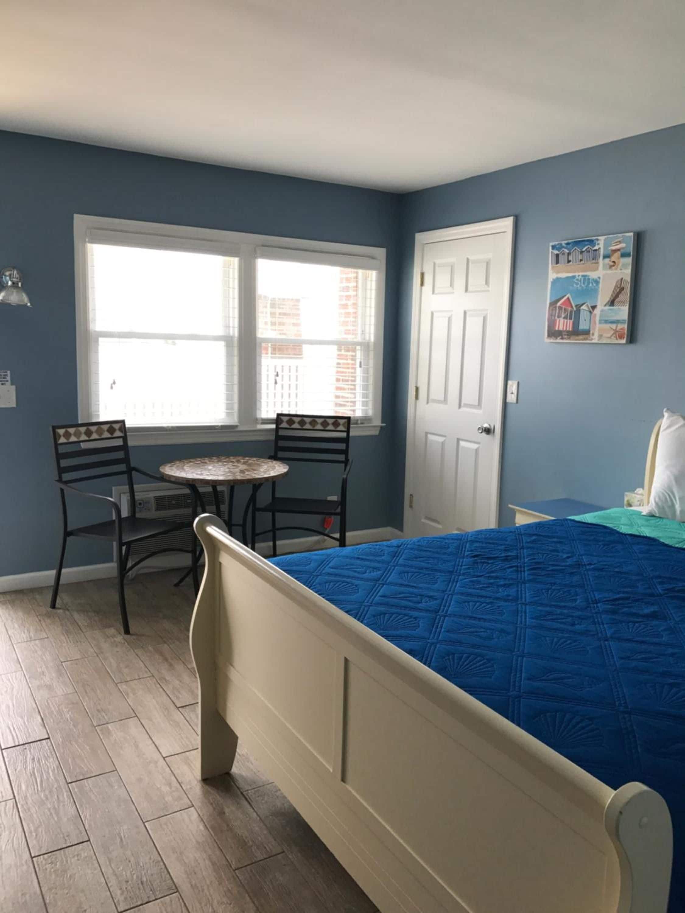 Een slaapkamer met een bed, twee stoelen, een tafel en een raam.