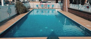 A rectangular swimming pool with a white fence and chairs around it. - Pelican Point Motel (Point Pleasant Beach)