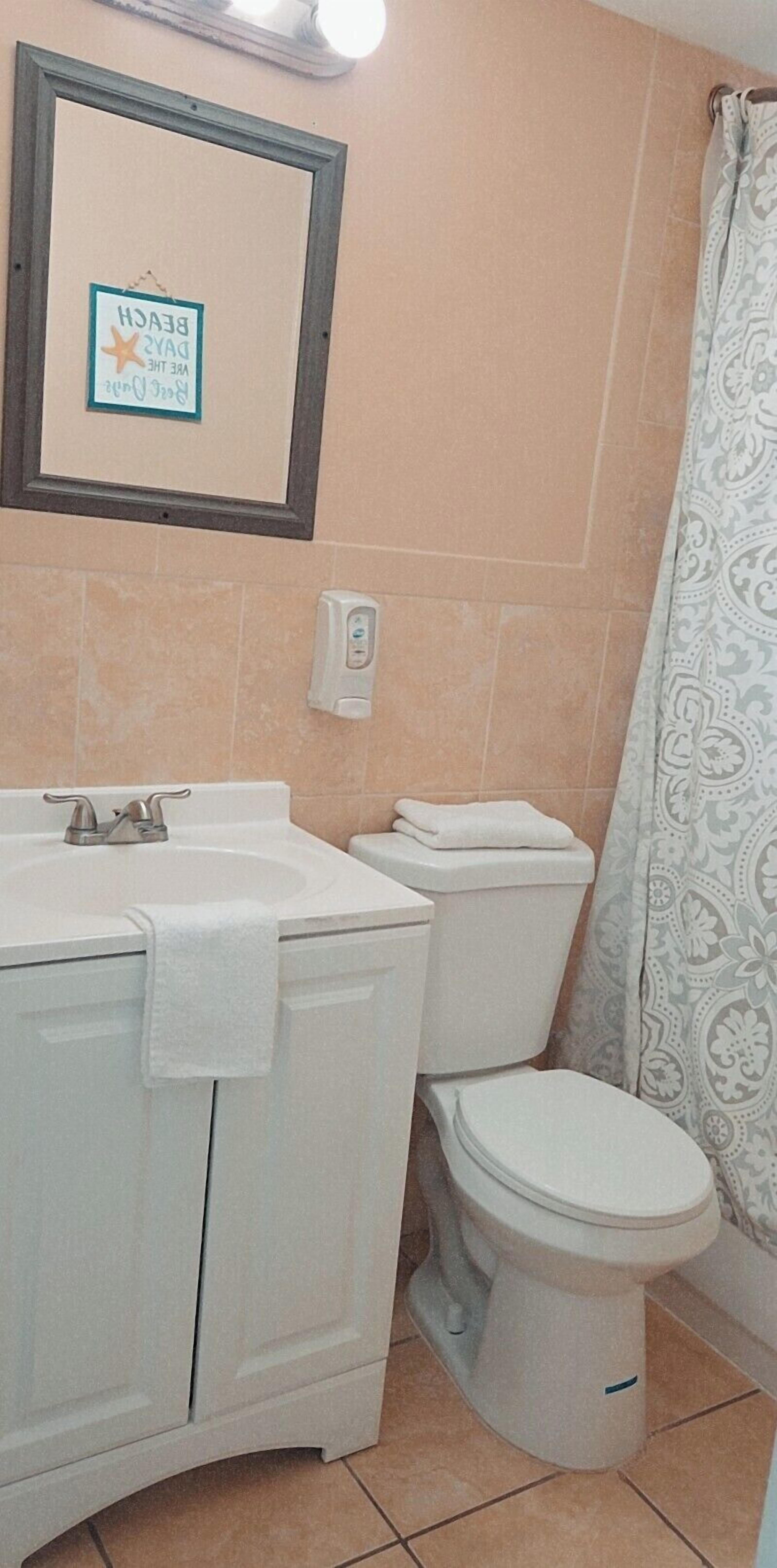 A bathroom with a sink, toilet, and a framed sign on the wall.