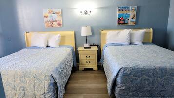 Quarto com duas camas, cada uma com cabeceira e peseira combinando, mesa de cabeceira com abajur e uma parede com pôster.