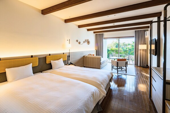 A hotel room with two beds, a desk, and a balcony with curtains.