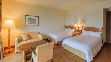 Een hotelkamer met twee bedden, een bank, een tafel en een lamp.